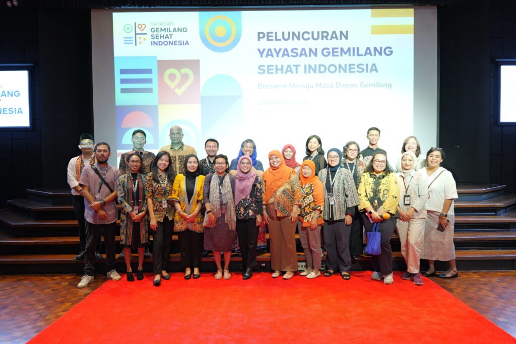 Foto bersama seluruh jajaran pengurus, mitra, dan pemangku kepentingan di atas panggung berkarpet merah saat acara peluncuran resmi Yayasan Gemilang Sehat Indonesia (YGSI) di Jakarta. Mereka berdiri berjejer dengan latar belakang layar proyektor besar bertuliskan "Peluncuran Yayasan Gemilang Sehat Indonesia".