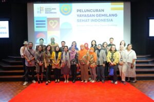 Foto bersama seluruh jajaran pengurus, mitra, dan pemangku kepentingan di atas panggung berkarpet merah saat acara peluncuran resmi Yayasan Gemilang Sehat Indonesia (YGSI) di Jakarta. Mereka berdiri berjejer dengan latar belakang layar proyektor besar bertuliskan "Peluncuran Yayasan Gemilang Sehat Indonesia".
